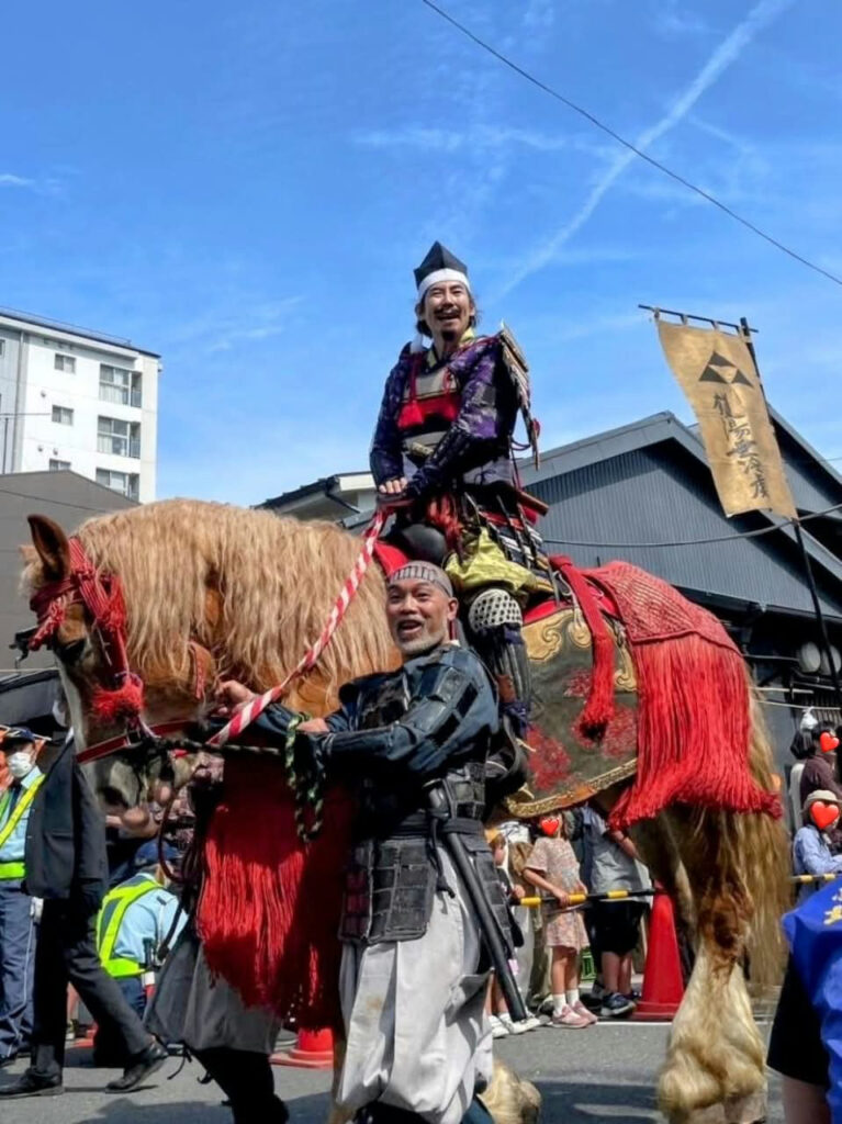 甲冑姿で武者行列の馬の口取りを務める様子