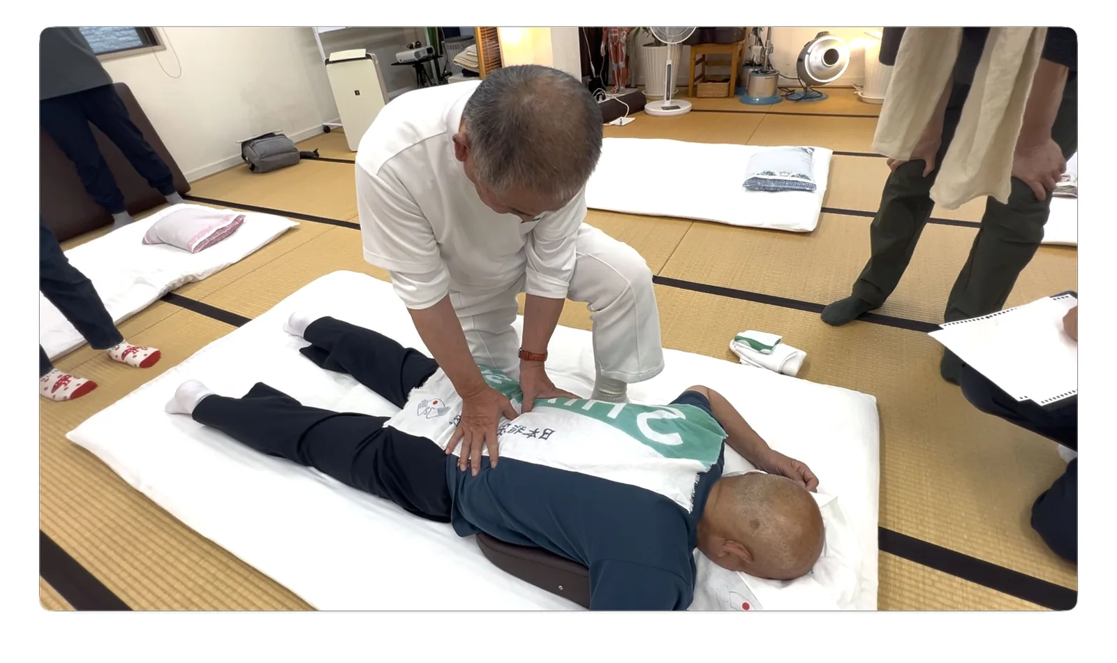 指尖で腰部を深く指圧する田中功先生